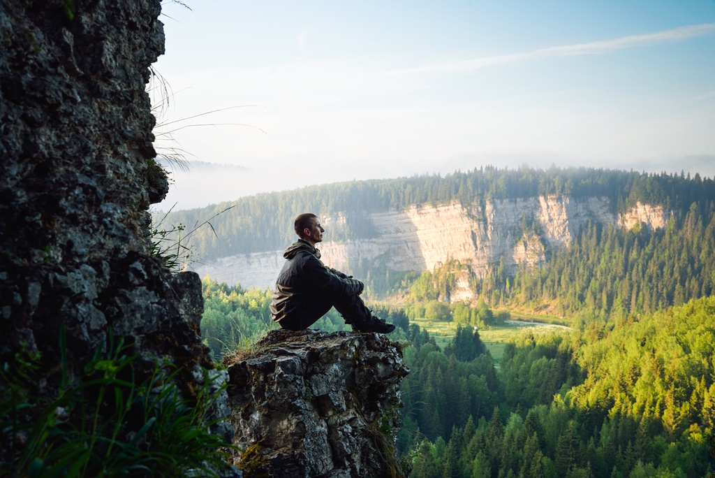 Man sitting on the top of the mountain, leisure in harmony with nature